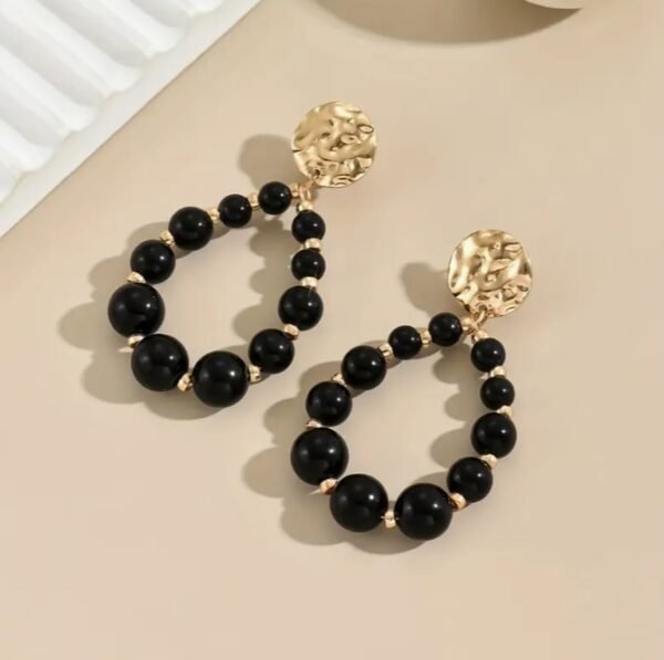 Capture d’écran 2025-09-17 115442 Boucles d'oreilles en perles noires tombantes avec accents dorés