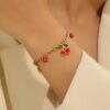 Bracelet doré à pendentif cerise et perles rouges