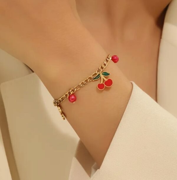 Bracelet doré à pendentif cerise et perles rouges