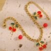 Bracelet doré à pendentif cerise et perles rouges